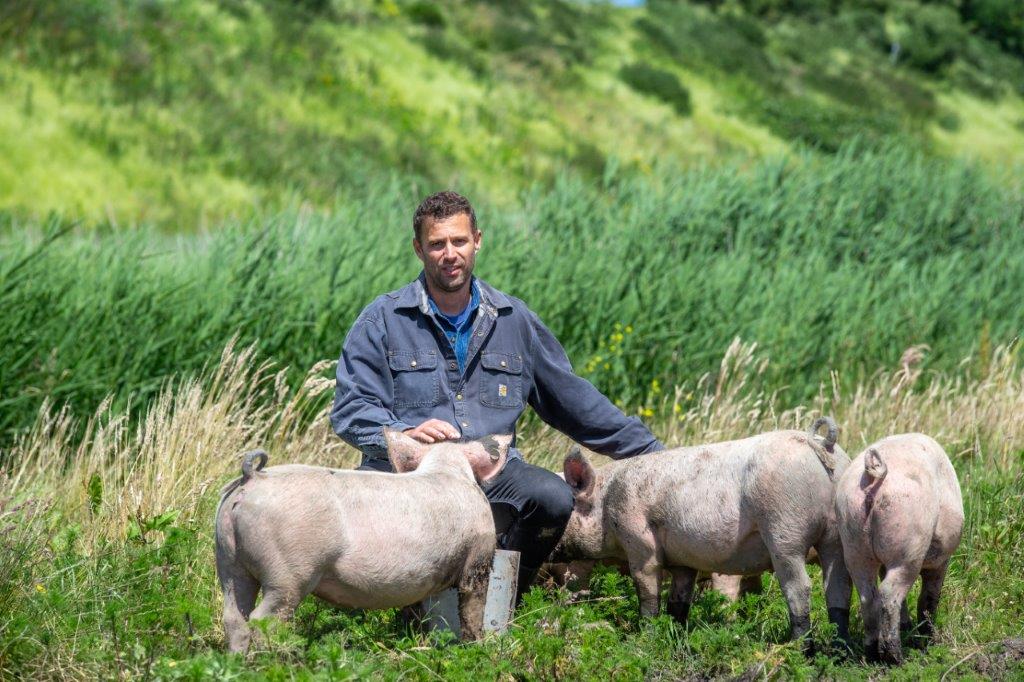 Dirk van De Herkomst knuffelend met varkens 